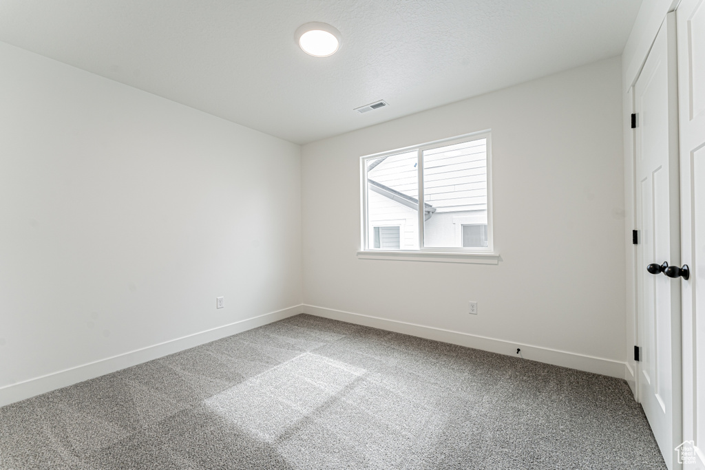 Empty room with visible vents, carpet flooring, and baseboards