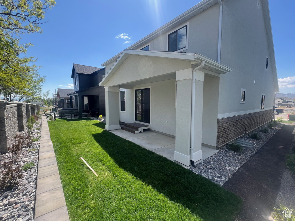 Back of property with a patio, stucco siding, a yard, and brick siding