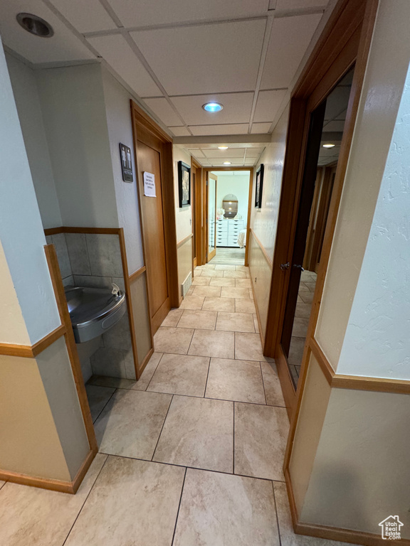 Hall featuring a paneled ceiling and light tile patterned floors