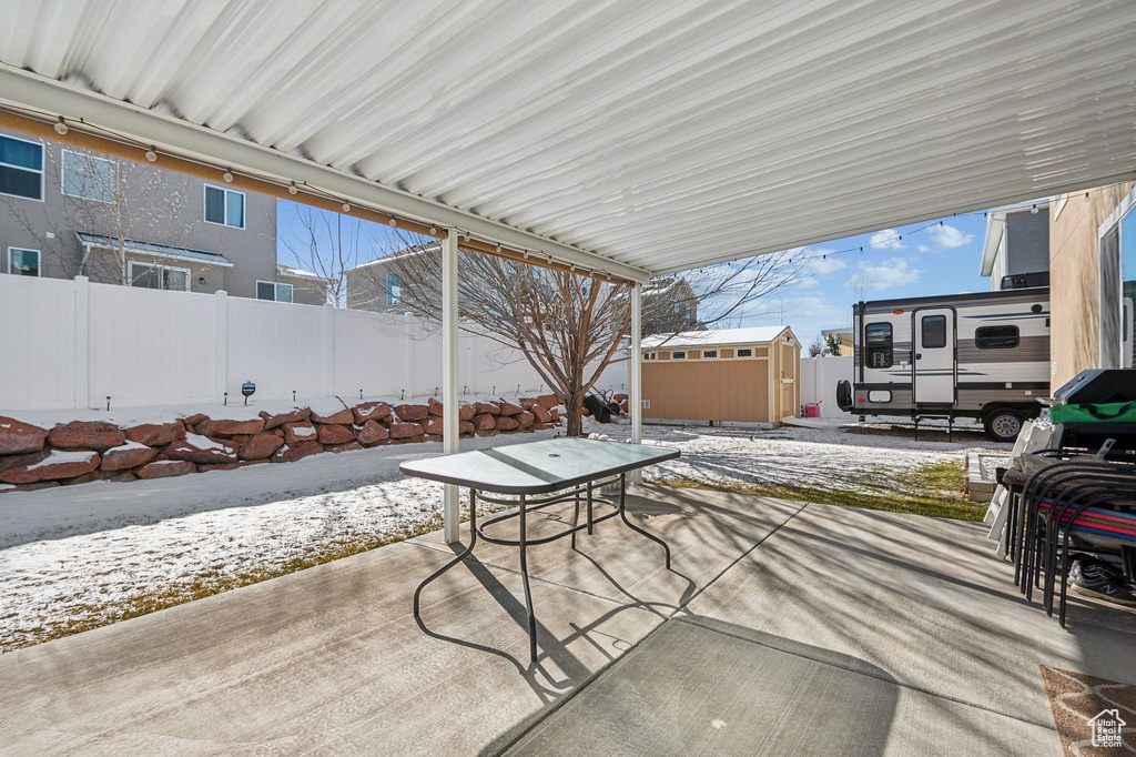 Snow covered patio featuring a storage shed