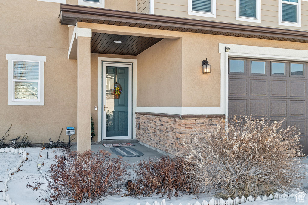 Snow covered property entrance with a garage