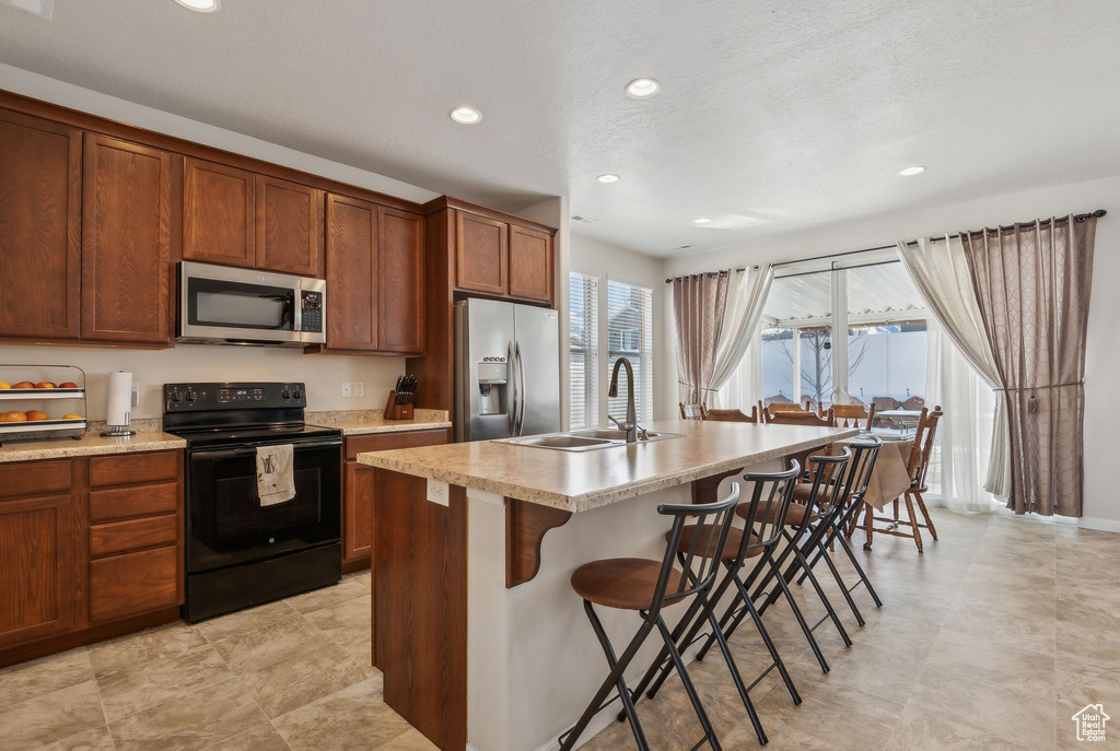 Kitchen with a breakfast bar, sink, stainless steel appliances, and a kitchen island with sink