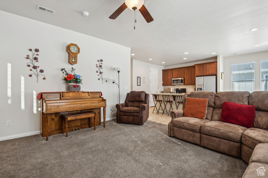 Carpeted living room featuring ceiling fan