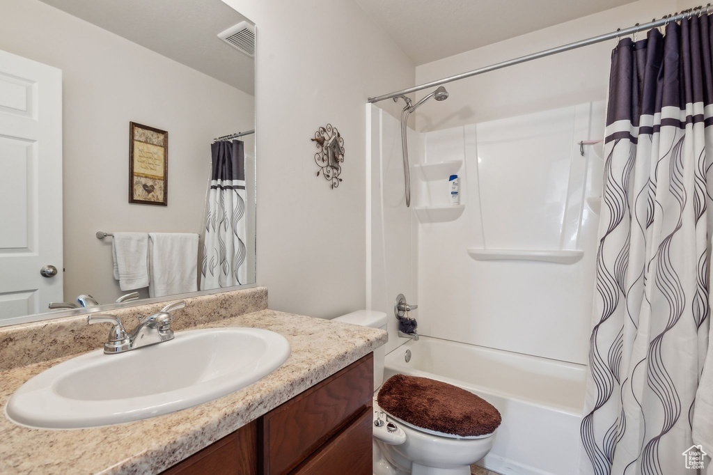 Full bathroom with toilet, shower / bath combo, and vanity