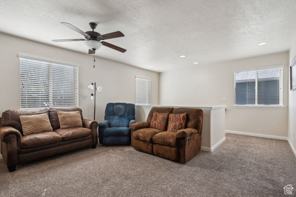 Living room featuring ceiling fan, a textured ceiling, and light carpet