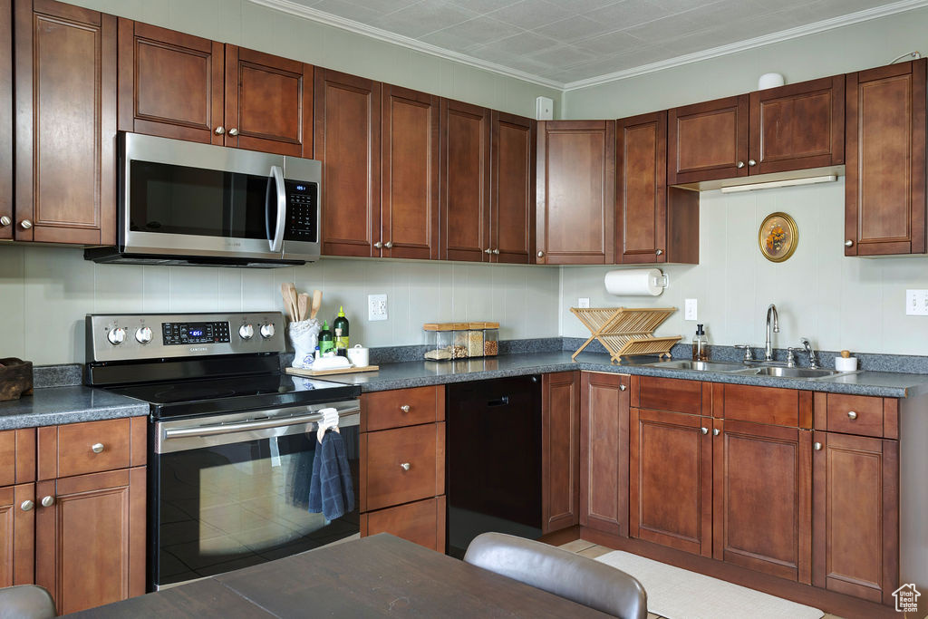 Kitchen featuring sink, appliances with stainless steel finishes, and crown molding