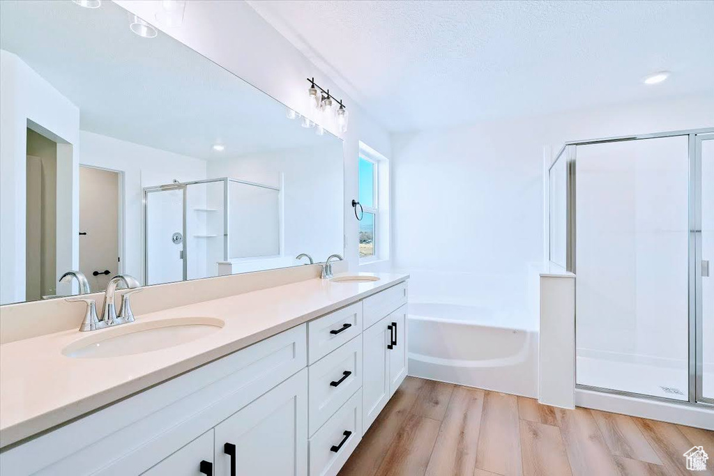 Bathroom with a shower stall, double vanity, a bath, wood finished floors, and recessed lighting
