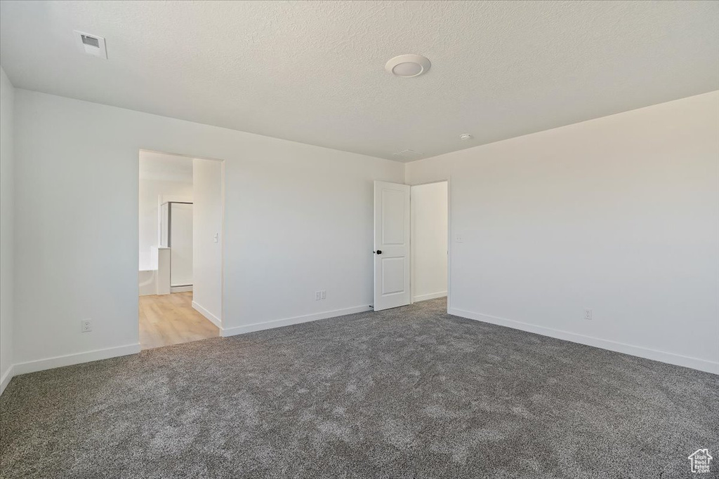 Carpeted empty room with a textured ceiling