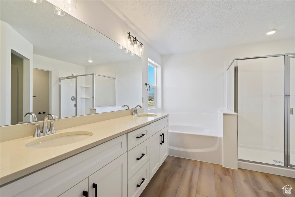 Bathroom featuring independent shower and bath, vanity, hardwood / wood-style floors, and a textured ceiling
