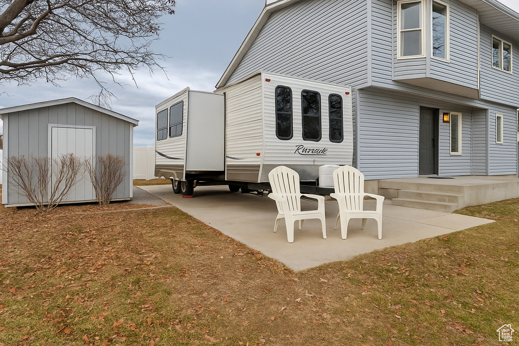 Rear view of property with a patio area, a shed, and an outbuilding