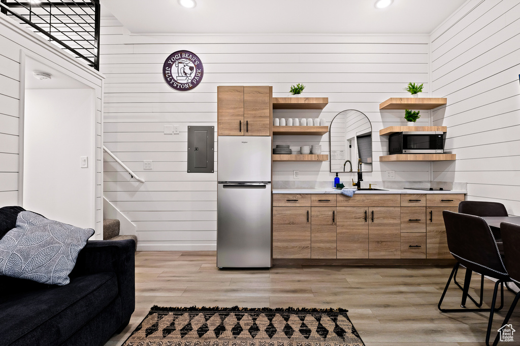 Kitchen featuring light hardwood / wood-style floors, electric panel, stainless steel appliances, and wooden walls