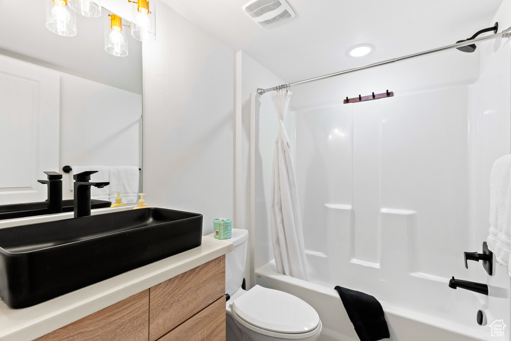 Full bathroom with toilet, shower / bathtub combination with curtain, and vanity