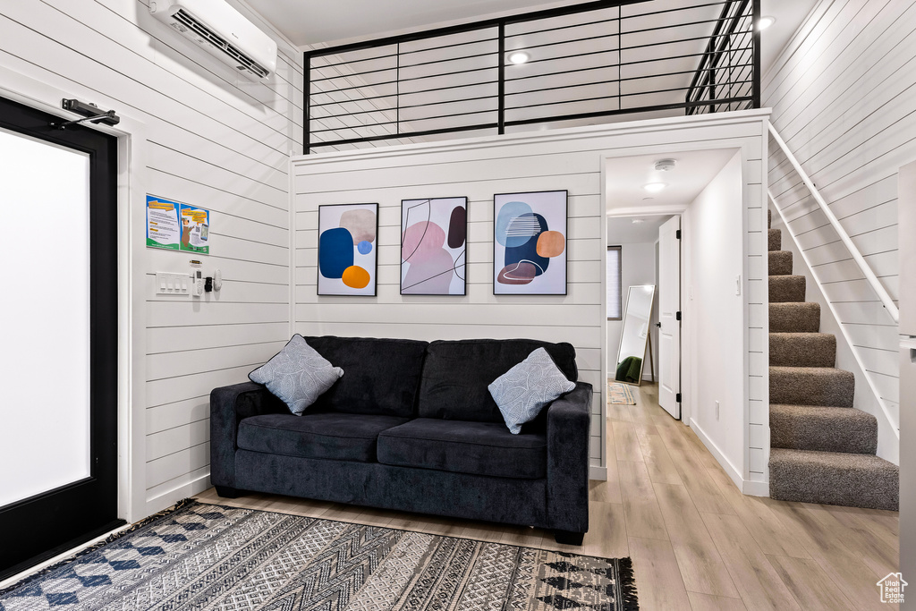 Living room with an AC wall unit, wood-type flooring, and a towering ceiling