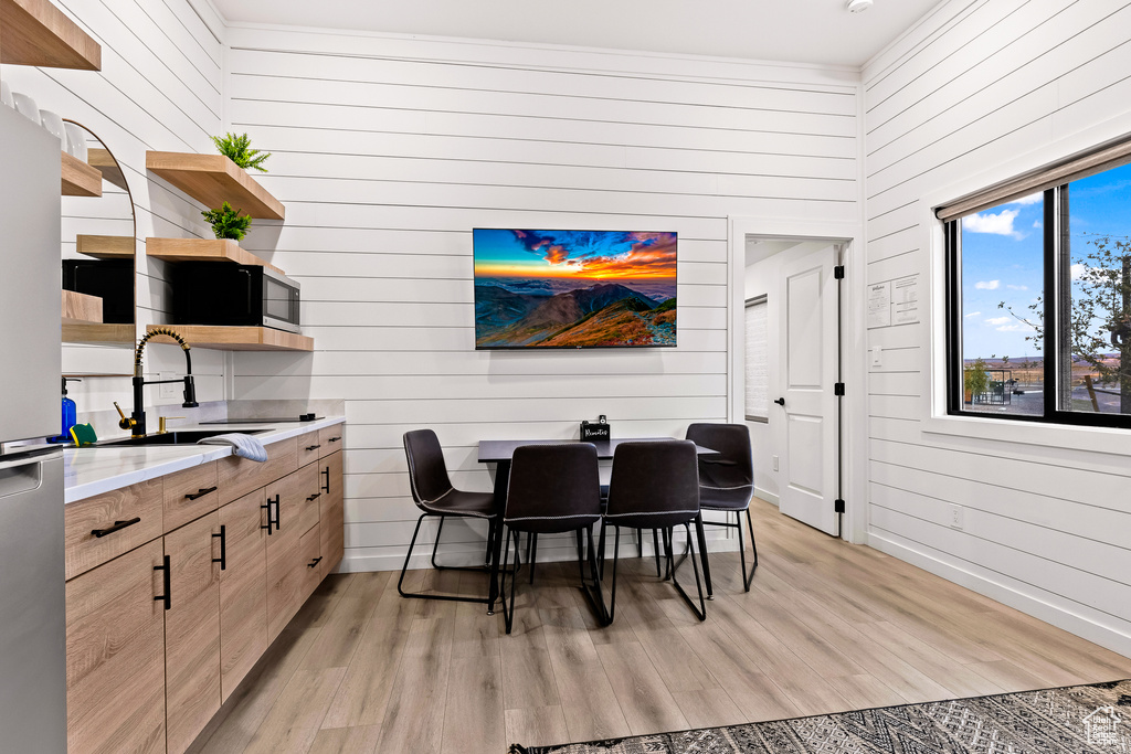 Dining area featuring sink, light hardwood / wood-style flooring, and wood walls