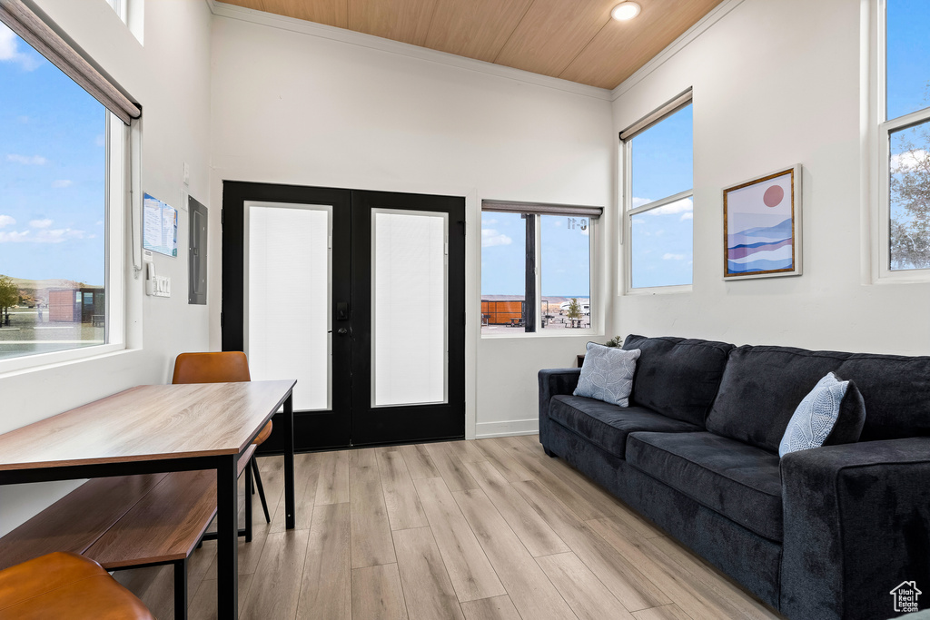 Living room with light wood-type flooring, french doors, crown molding, and wooden ceiling