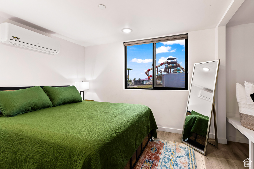 Bedroom with a wall unit AC, a wall of windows, and wood-type flooring