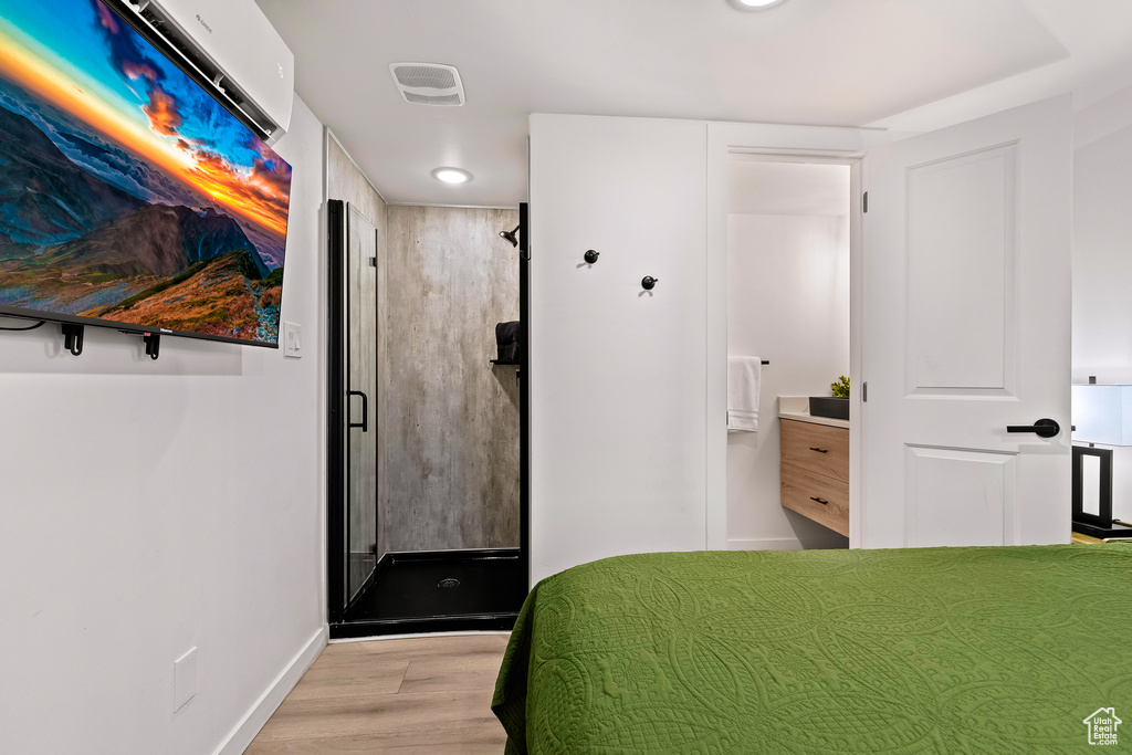 Unfurnished bedroom featuring connected bathroom and light hardwood / wood-style flooring