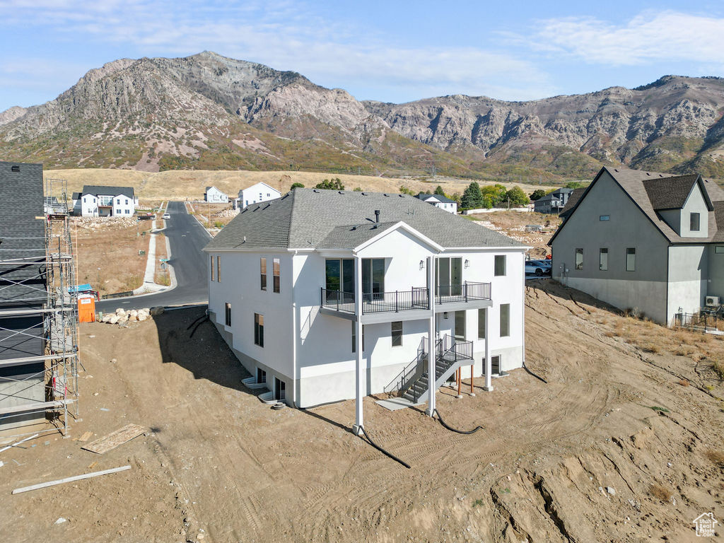 Back of house with a mountain view and a balcony