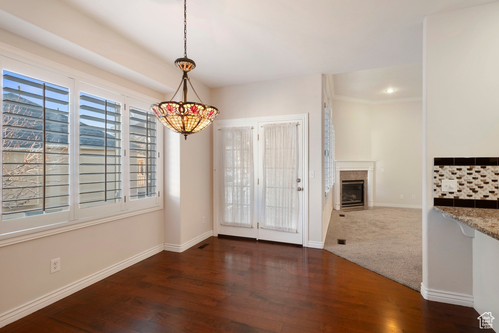 Unfurnished dining area featuring dark hardwood / wood-style flooring and crown molding