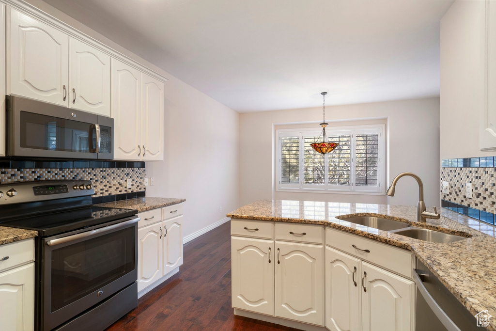 Kitchen featuring light stone countertops, appliances with stainless steel finishes, backsplash, and sink