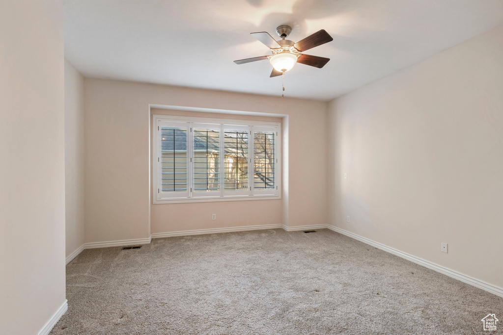 Carpeted spare room featuring ceiling fan