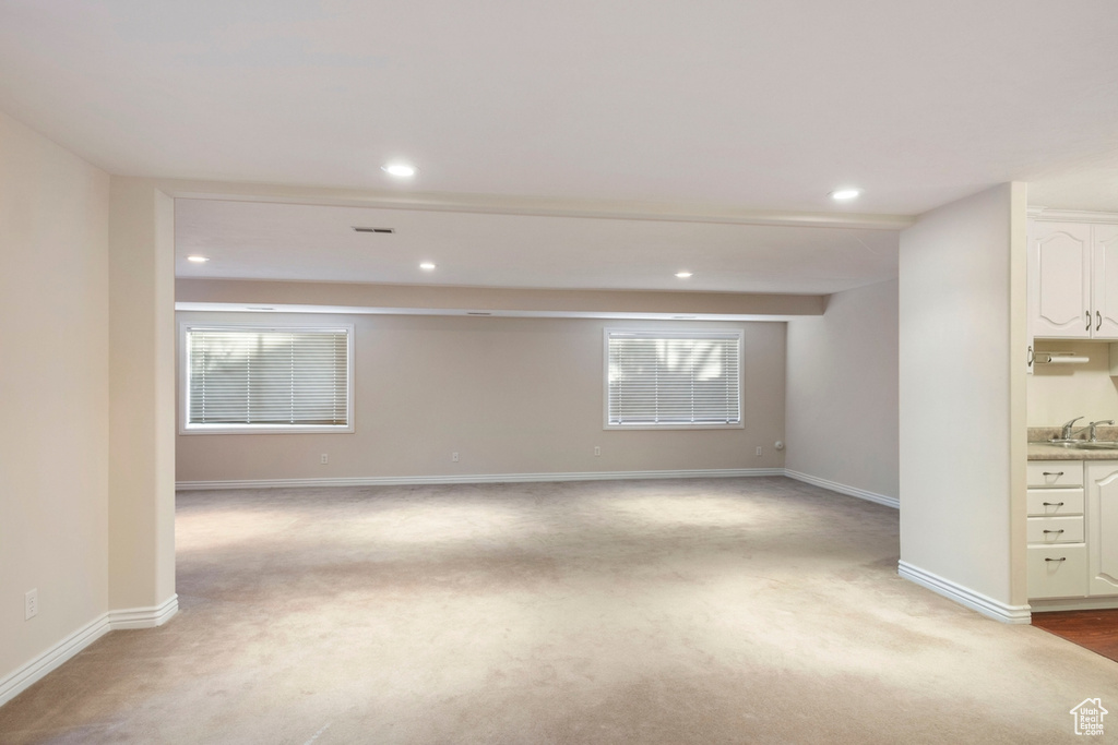 Carpeted spare room featuring a healthy amount of sunlight and sink