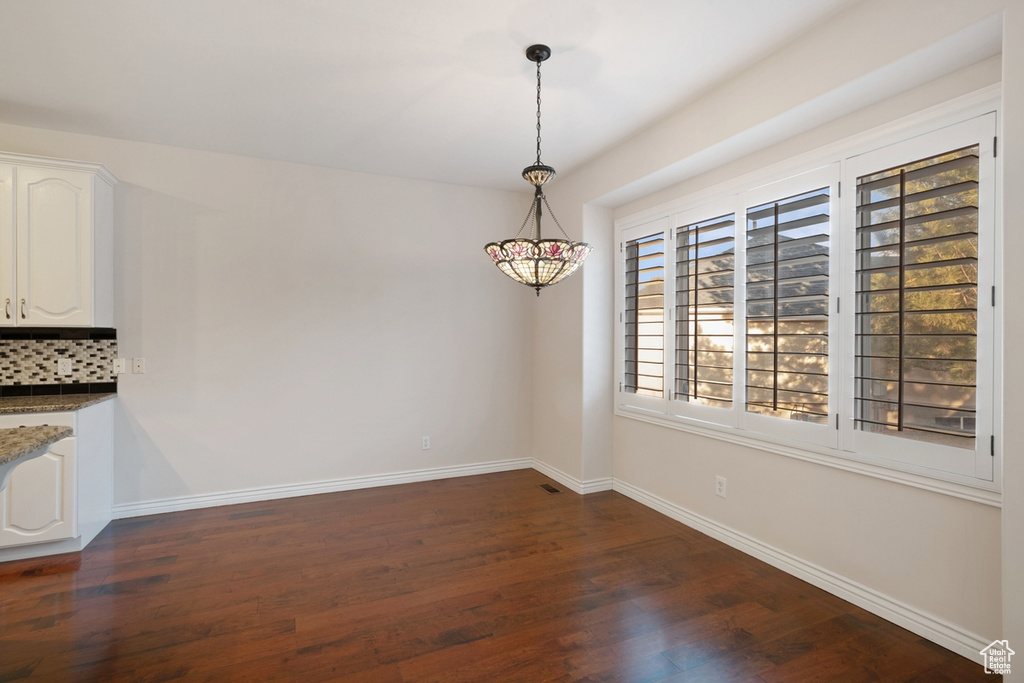 Unfurnished dining area featuring dark wood-type flooring