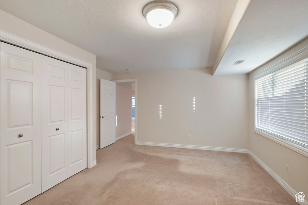 Unfurnished bedroom with light carpet and a closet