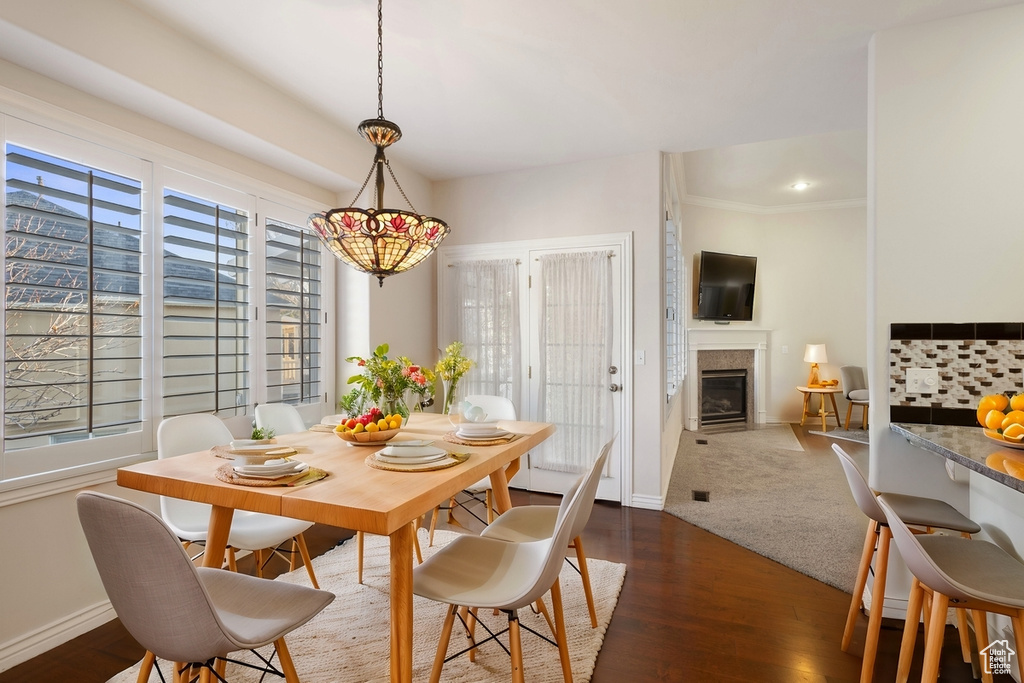 Dining area with dark wood-type flooring and crown molding