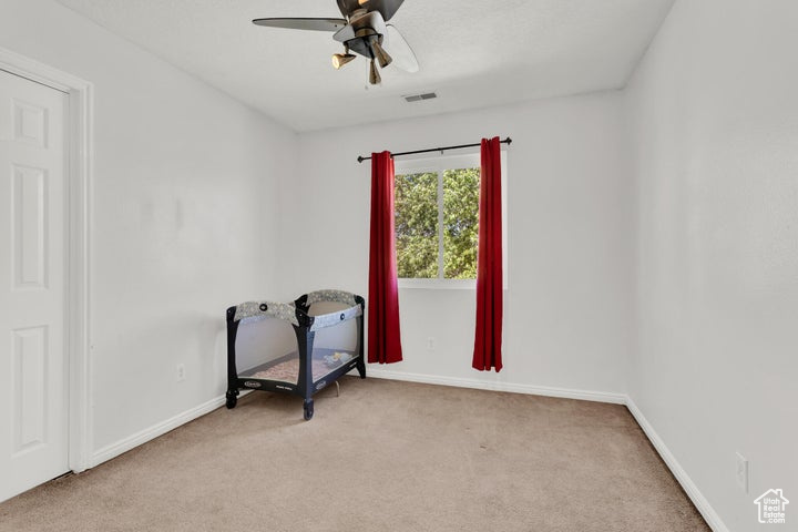 Carpeted empty room featuring ceiling fan