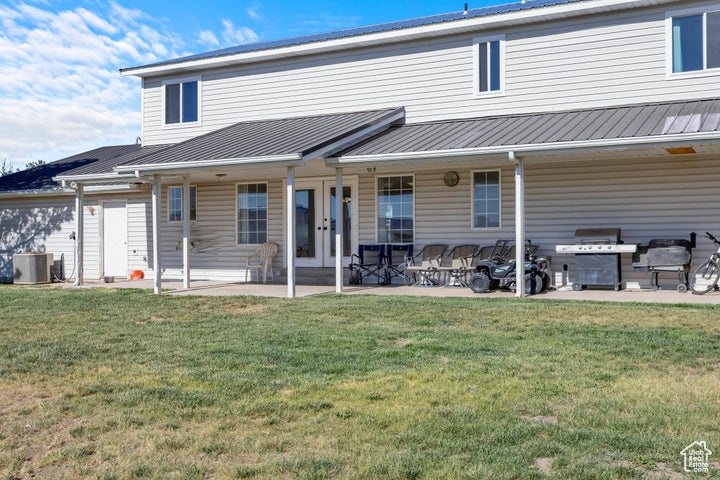 Back of house with a patio area, a yard, and central AC