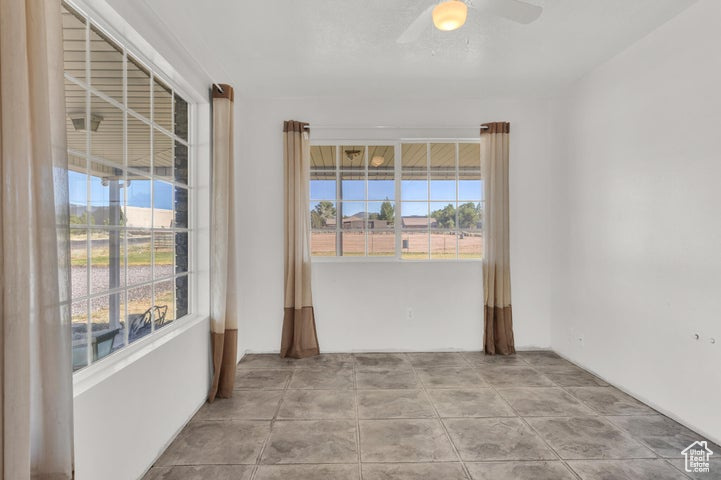 Empty room with ceiling fan and a wealth of natural light
