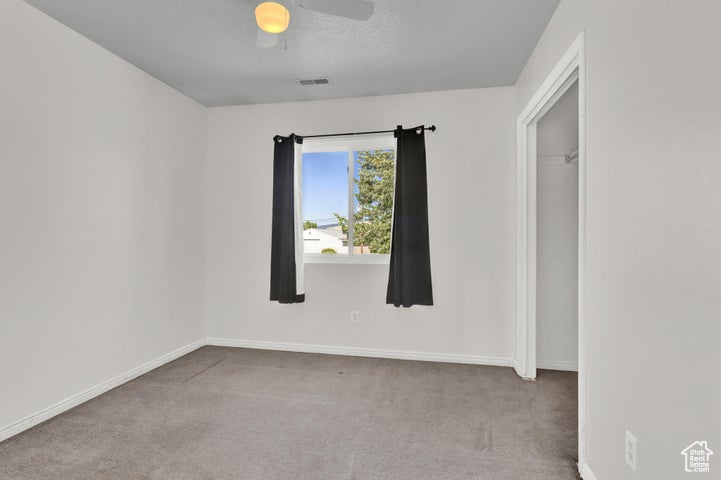 Carpeted spare room with ceiling fan
