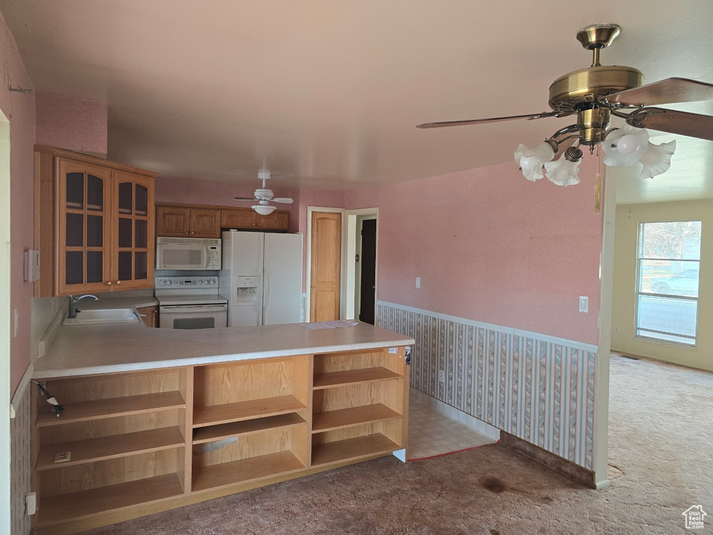 Kitchen with sink, white appliances, kitchen peninsula, and light colored carpet