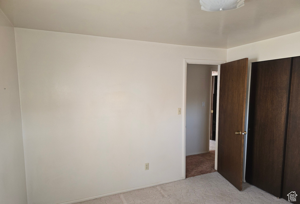 Unfurnished bedroom featuring a closet and light colored carpet
