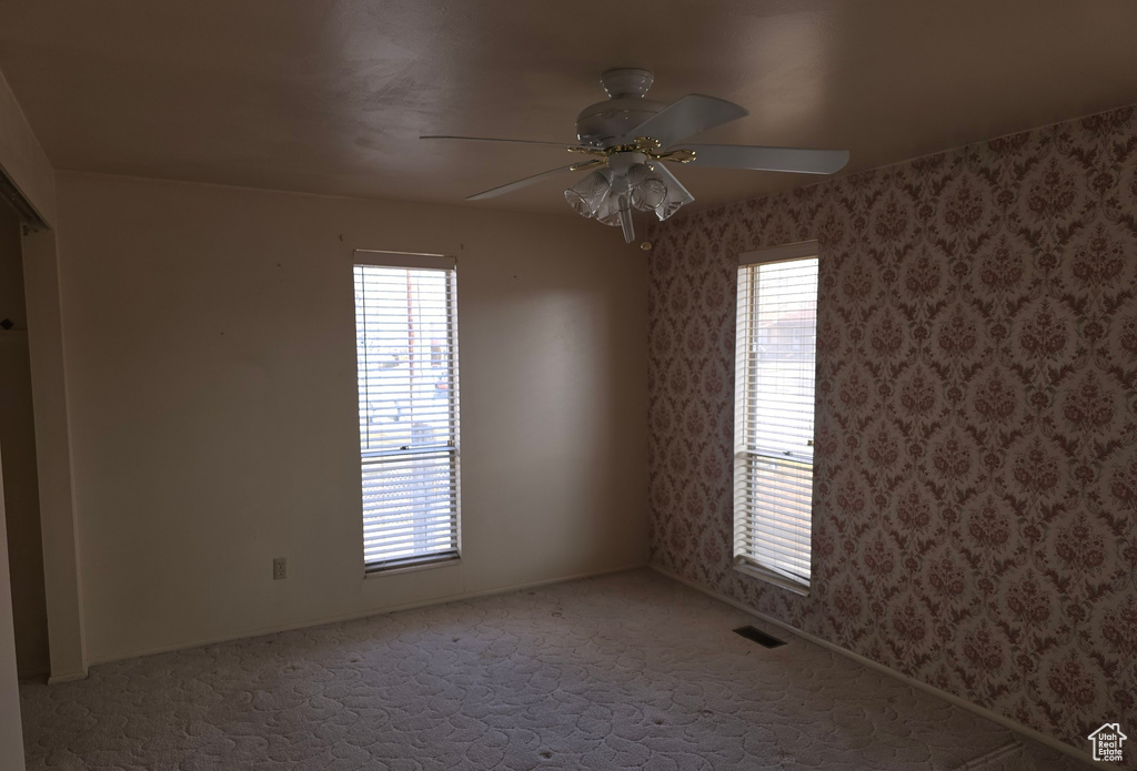 Empty room with ceiling fan and carpet flooring