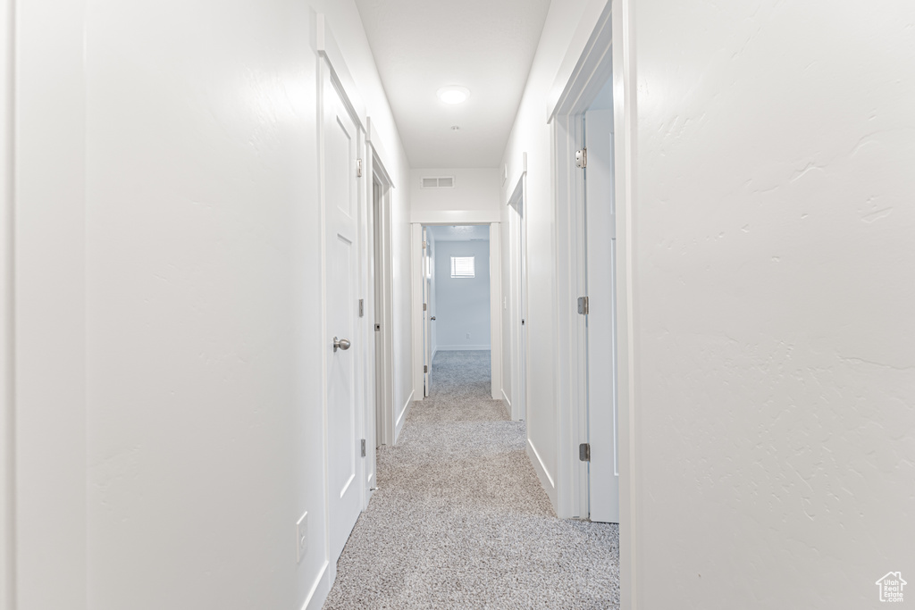 Hallway featuring baseboards and light carpet