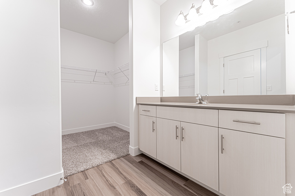 Bathroom with vanity, wood finished floors, and a walk in closet