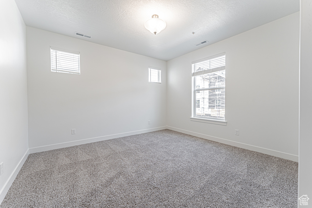 Spare room featuring light carpet and a textured ceiling