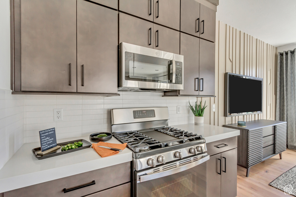 Kitchen with tasteful backsplash, light hardwood / wood-style flooring, and stainless steel appliances