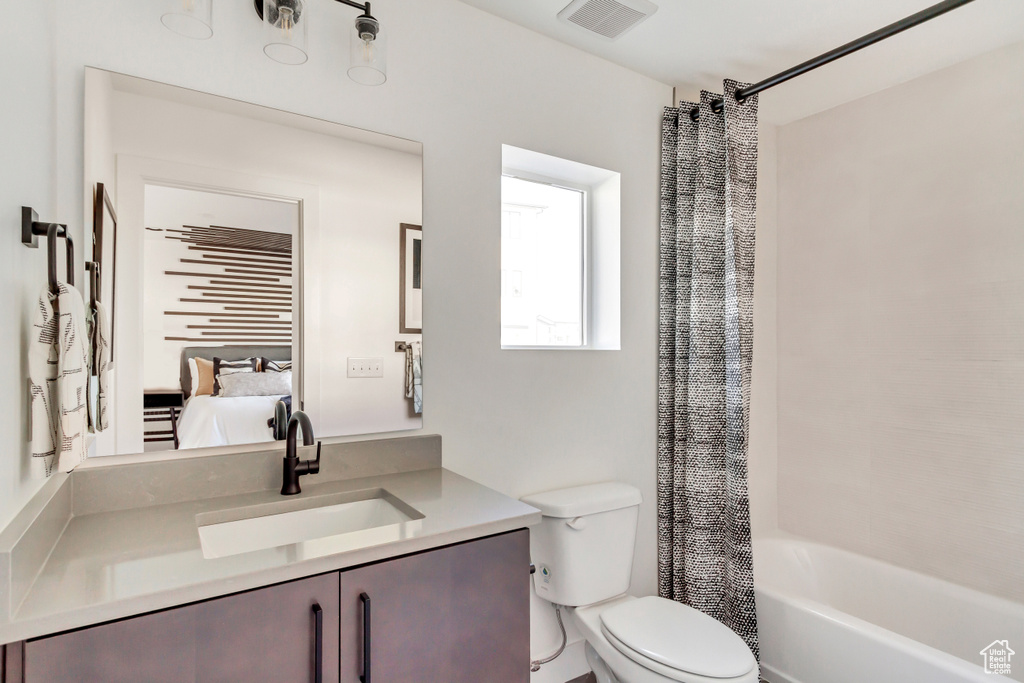 Full bathroom featuring toilet, shower / bath combination with curtain, and vanity