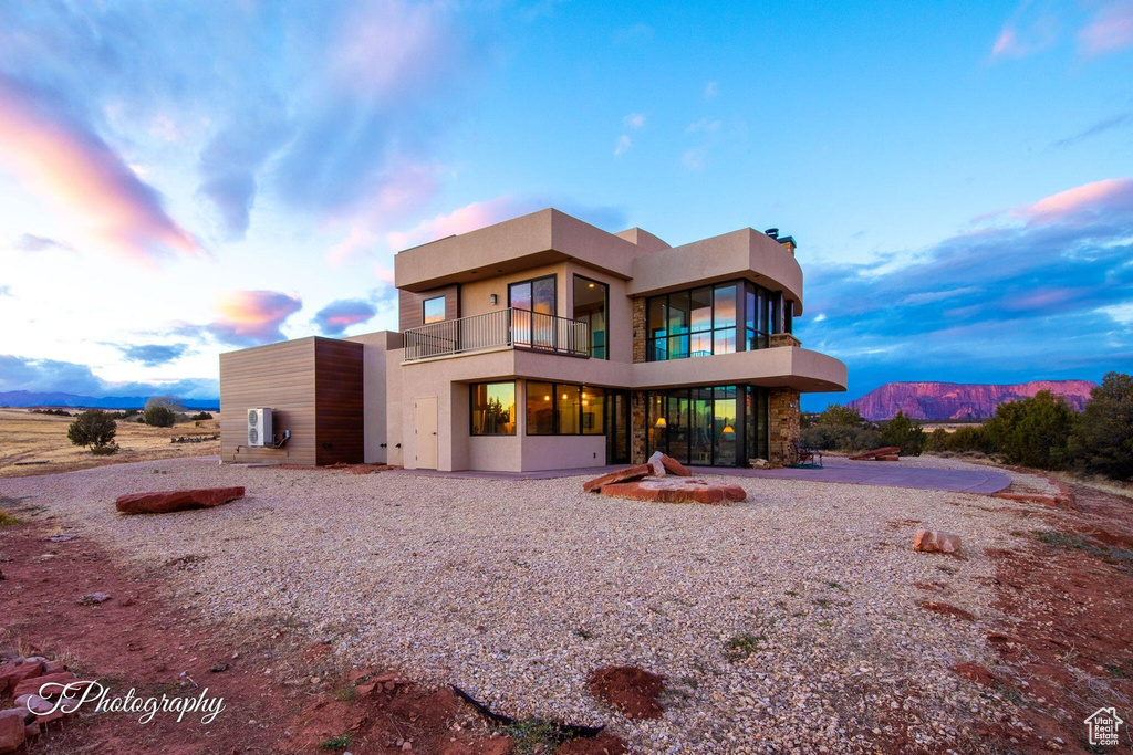 Back house at dusk featuring a balcony and a mountain view