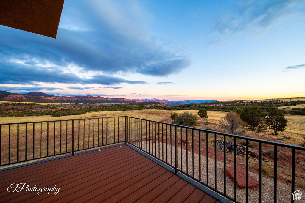 Deck at dusk featuring a rural view and a mountain view