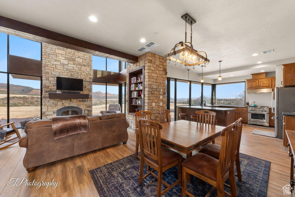 Dining space featuring an inviting chandelier, a fireplace, light wood-type flooring, and plenty of natural light