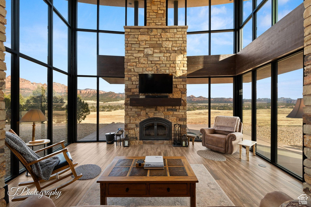 Living room featuring a high ceiling, hardwood / wood-style flooring, a fireplace, and a wealth of natural light