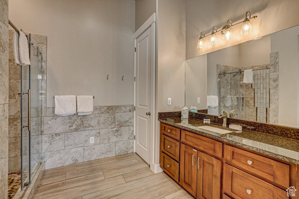 Bathroom featuring a shower with shower door and vanity