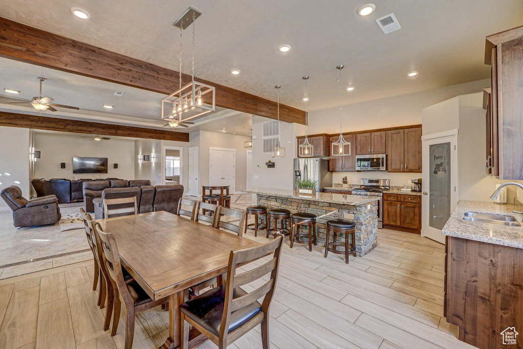 Dining area with ceiling fan, sink, and beamed ceiling