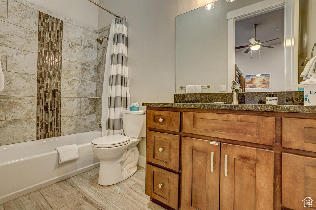 Full bathroom featuring shower / bath combo with shower curtain, toilet, ceiling fan, and vanity