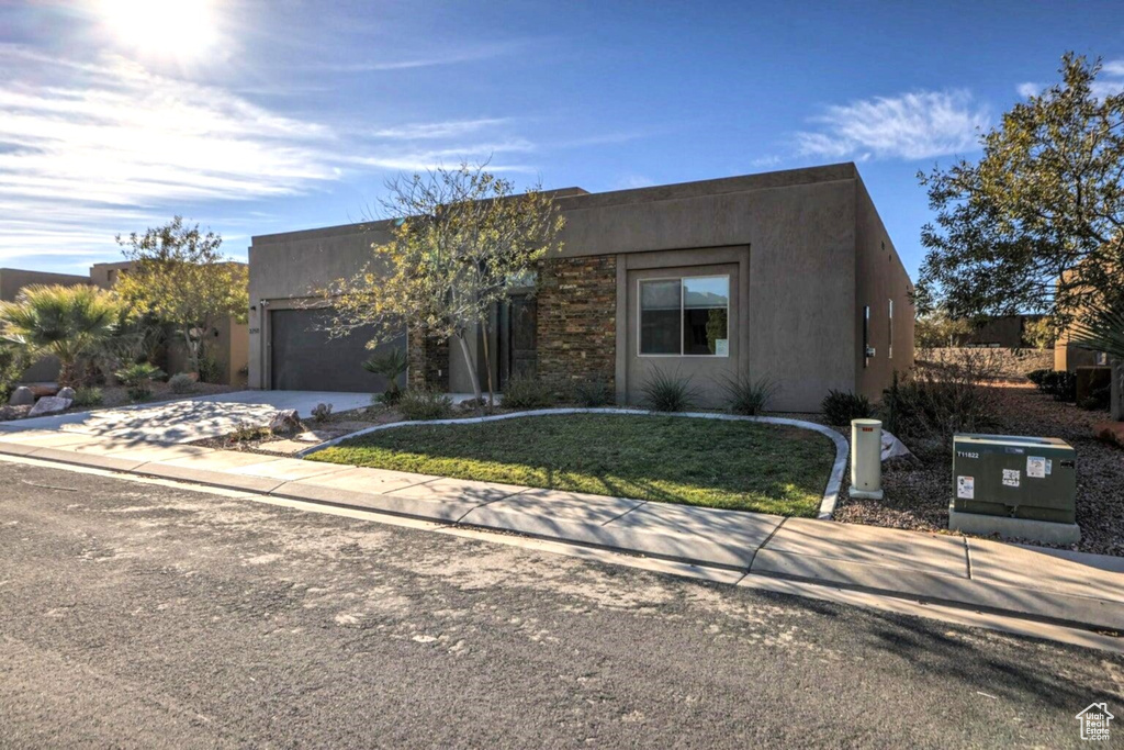 Southwest-style home with stucco siding, a garage, a front lawn, and concrete driveway