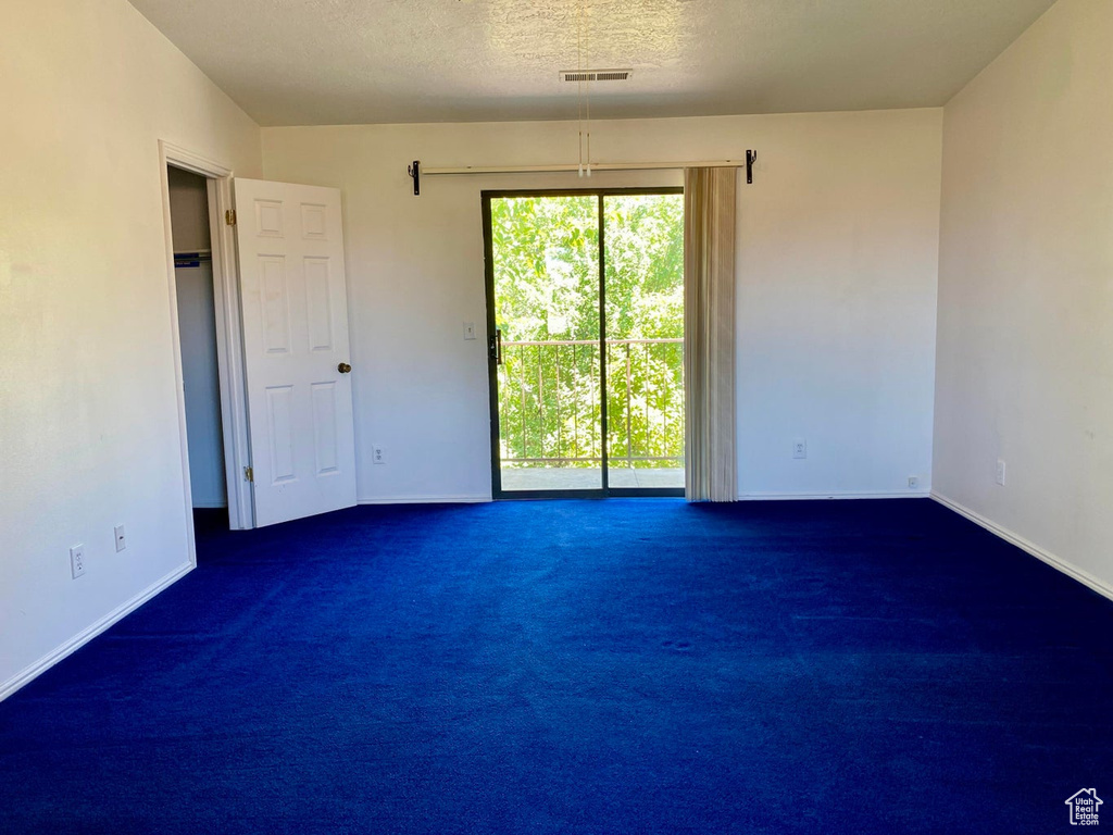 Spare room with dark carpet and a textured ceiling
